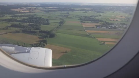 Green fields, trees and European settlement are seen through window of aircraft. Stock Footage 91784208