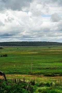 Green fields in the village. Cloudy sky over the fields. Highway in the dis.. Stock Photos