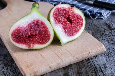 A green fig cut in half on rustic background Stock Photos
