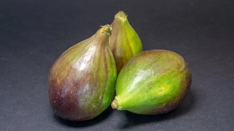 Green figs, three fruits on a light dark background, close-up Stock Photos