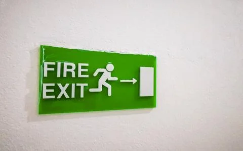 Green fire exit emergency sign mounted on wall safety Thailand. Stock Photos