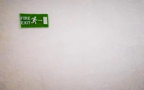 Green fire exit emergency sign mounted on wall safety Thailand. Stock Photos