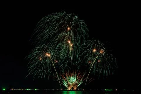 Green Fireworks Exploding Over Ocean Water At Night Long Exposure Shot 스톡 사진