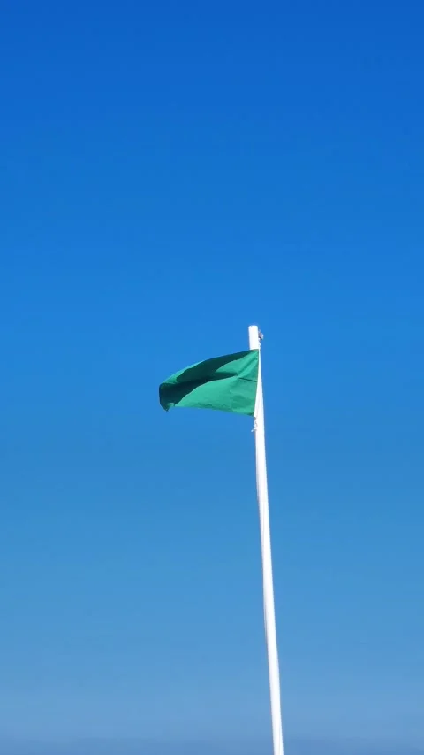 Green flag waving at a beach Stock Footage 279743663
