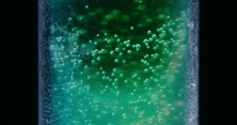 Green fluid with bubbles in a vial. black background. Cinematic shot. Stock Footage 237156426