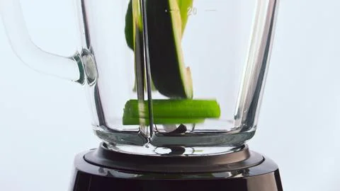 Green fruits vegetables falling blender cup in super slow motion close up. Stock Photos
