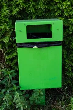 Green garbage bin front view with black plastic inside for rubbish around green Stock Photos
