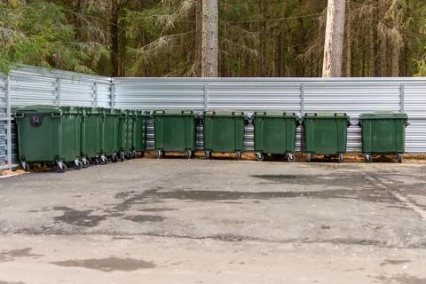 Green garbage cans stand on the paved area. Stock Photos