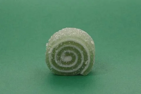 Green gelatin candy on a background of the same color. Stock Photos