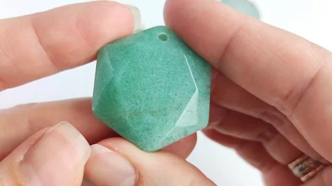 Green gemstone pendant featuring hexagonal faceted crystal shapes Stock Footage 345139604