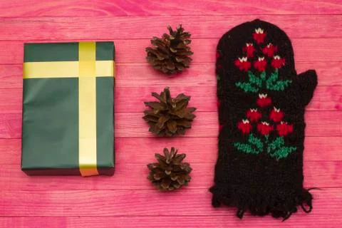 Green gift box and pine cone with mitten Stock Photos