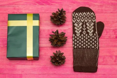 Green gift box and pine cone with mitten Stock Photos