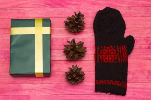 Green gift box and pine cone with mitten Stock Photos