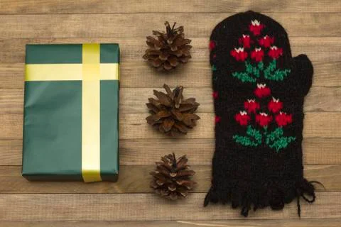 Green gift box and pine cone with mitten Stock Photos