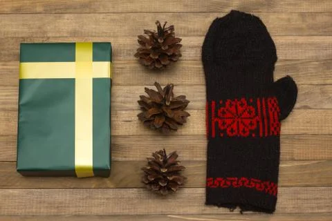Green gift box and pine cone with mitten Stock Photos