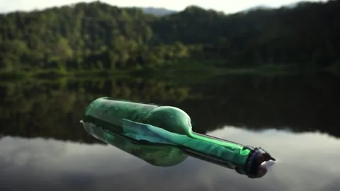 A green glass bottle with message float on lake Stock Footage 317295631