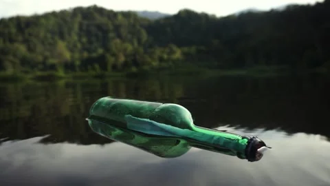 A green glass bottle with message float on lake Stock Footage 317295948