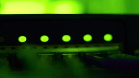 Green glowing indicator lights on a dark electronic server equipment panel Stock Footage 340355922