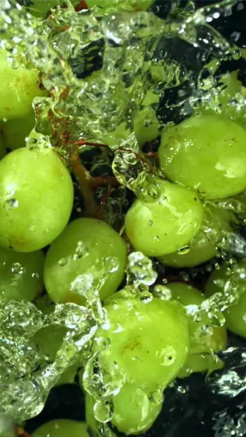 Green grapes fall with splashes into the water. Top view. Filmed on a high-speed Stock Footage 335321718