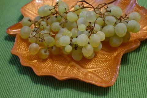 Green grapes on a grape leaf shaped plate Stock Photos