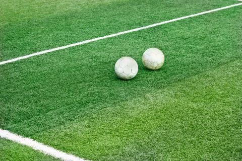 Green grass field with white mark line and two old football soccer, soft focus Foto stock