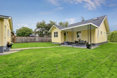 Green grass filled back yard of American yellow house. Northwest, USA Stock Photos