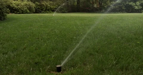 Green grass, irrigation system sprinkler, high angle, multiple  sprinkler heads Stock Footage 137932345
