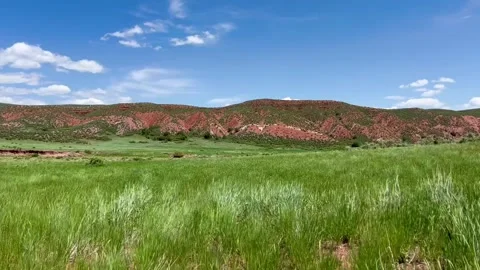 Green Grass Meadow Below Red Rock Hills Under Blue Sky Stock Footage 339399866