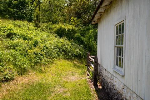 Green grass path around colonial whitewashed house with antique window Stock Photos