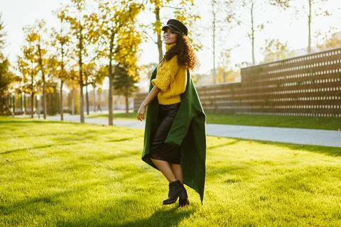 On the green grass throwing on one shoulder a dark green coat in a bright yellow Stock Photos