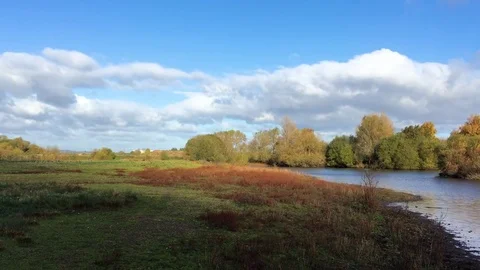 Green Grassy Fields rolls down to a rippling flowing river in the sunshine 動画素材 72634934