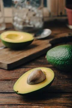 Green halved avocado on rustic kitchen table Stock Photos