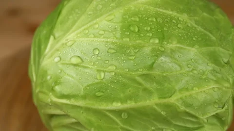 Green Head of Cabbage with Water Drops Rotates on a Wooden Turntable Stock Footage 246144483