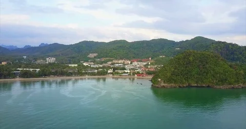 Green headland closing one end of a wide resort bay Видео 71298188