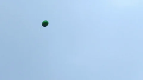 Green helium ballon floating and spinning in the air. Ballon moved by the wind. Stock Footage 80445562