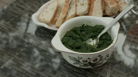 Green herb dip with sliced bread served on glass table in decorative bowl Stock Footage 345266225