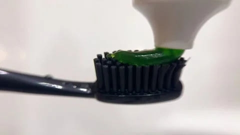 Green herbal toothpaste on black toothbrush for daily oral hygiene Stock Footage 320742845