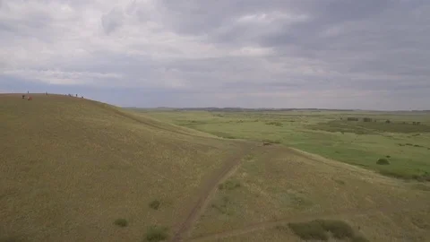 Green hill with people, summer, aerial view. Grassy hill and dirt road top view Stock Footage