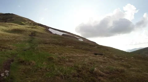 Green hill, some snow and a slow cloud slowly opens the sun Stock Footage 40700606