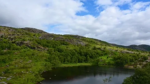 Green hills and clouded sky near a lake with trees in Norway during summer .. Stock Footage 340213006