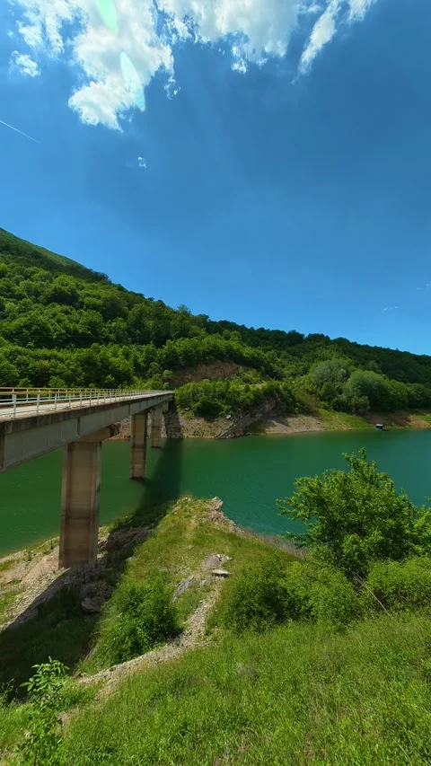 Green hills roll behind the bridge. Zavoj Lake, Serbia. Vertical Stock Footage 337495817