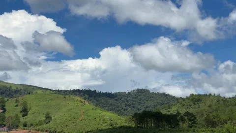Green hills stretch beneath a cloudy sky in a peaceful natural landscape. Scenic Stock Footage 338001685