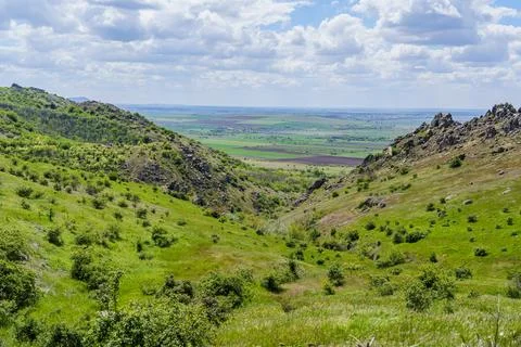 Green hills stretch under clouds in a valley with distant fields in the Foto stock