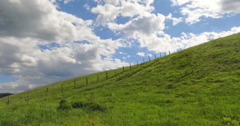 Green Hillside Under a Dynamic Cloudscape Stock Footage 303975421