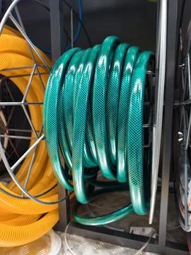 Green hose rolled into a compact coil is presented in a retail hardware sto.. Foto stock