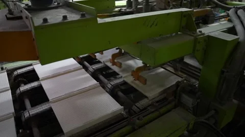 Green hydraulic press forms white ceramic tile sheets on an automated Stock Footage 346737953