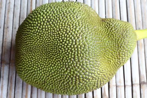 Green jackfruit has sharp spines on the bamboo background. Stock Photos