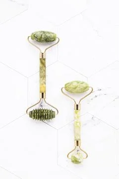 Green jade face rollers on a white marble background. SPA concept. Top view,  Stock Photos
