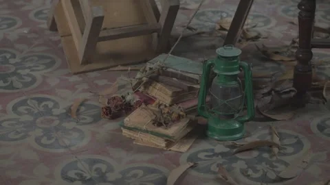 A green lantern sits on a carpeted floor next to a stack of books Stock Footage 331624450