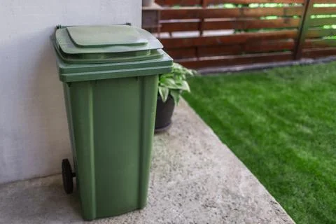 Green large plastic bin for trash on backyard. Stock Photos